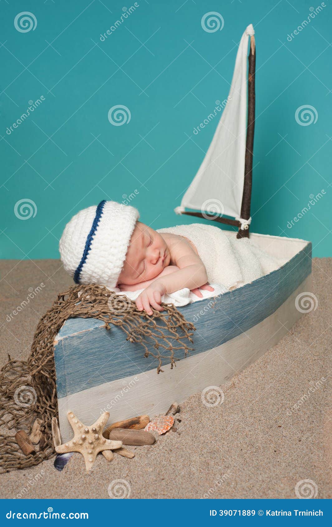  - newborn-baby-boy-sailor-sleeping-sailboat-one-week-old-wearing-white-blue-hat-little-surrounded-sand-39071889
