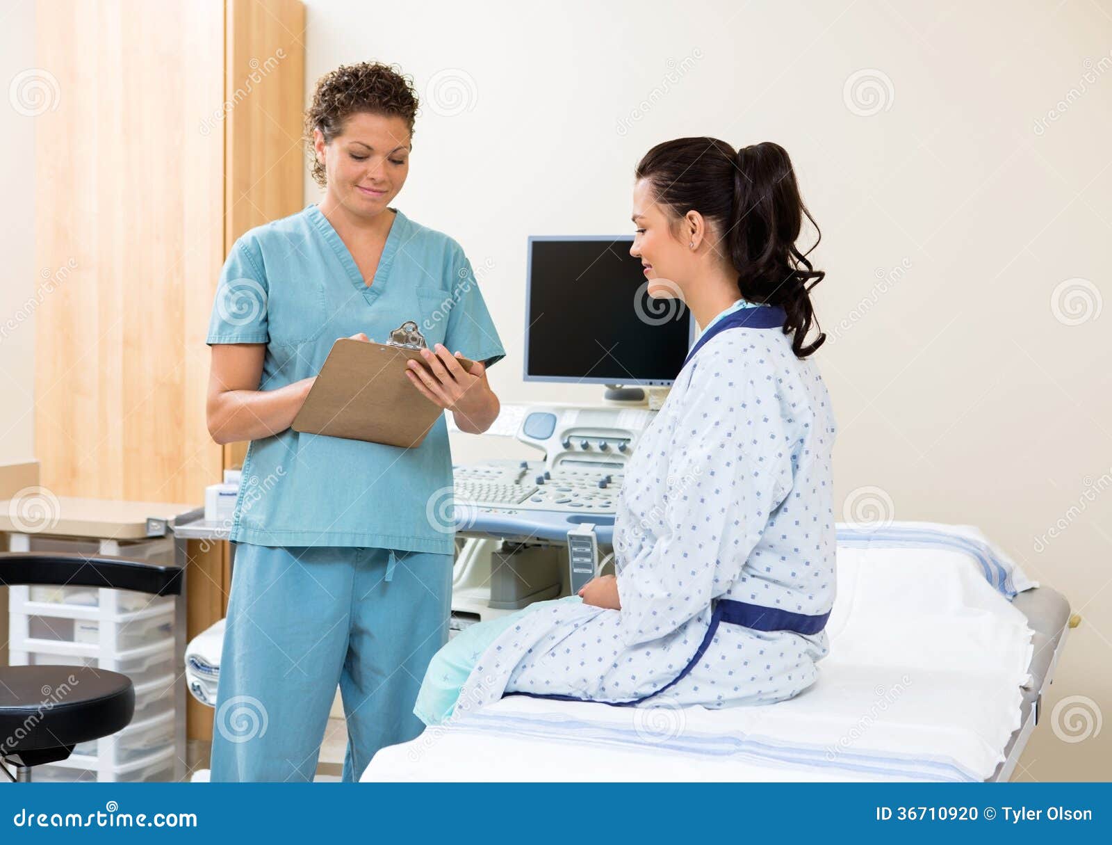 Nurse Writing Notes With Patient Sitting On Bed Stock