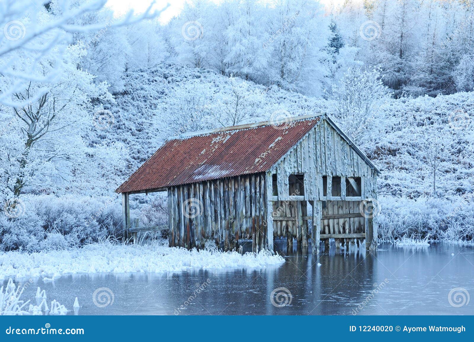 An old decaying boat house on the edge of an ice covered loch with 