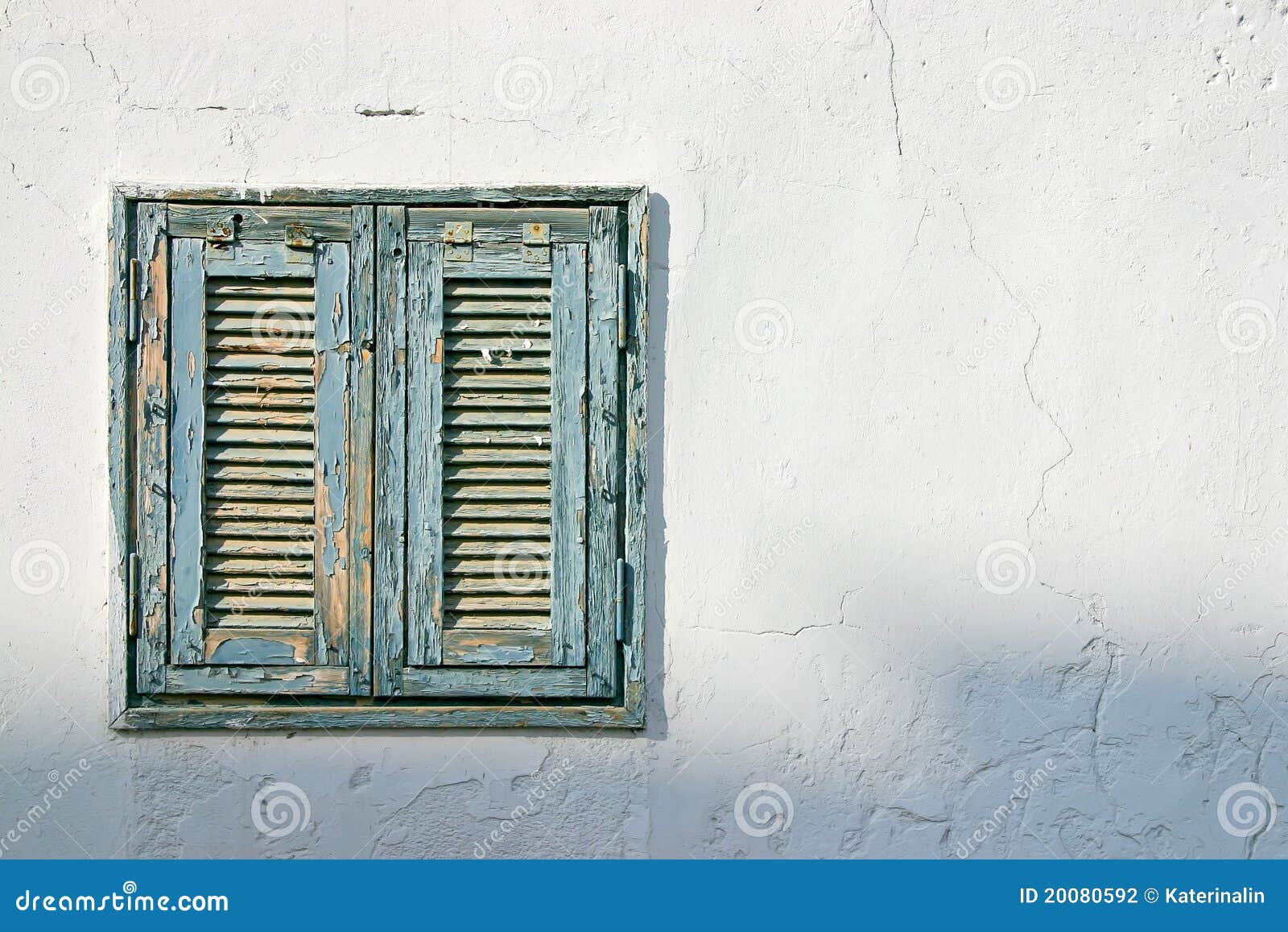 The old window with blue shutters on a white wall. Vintage background 