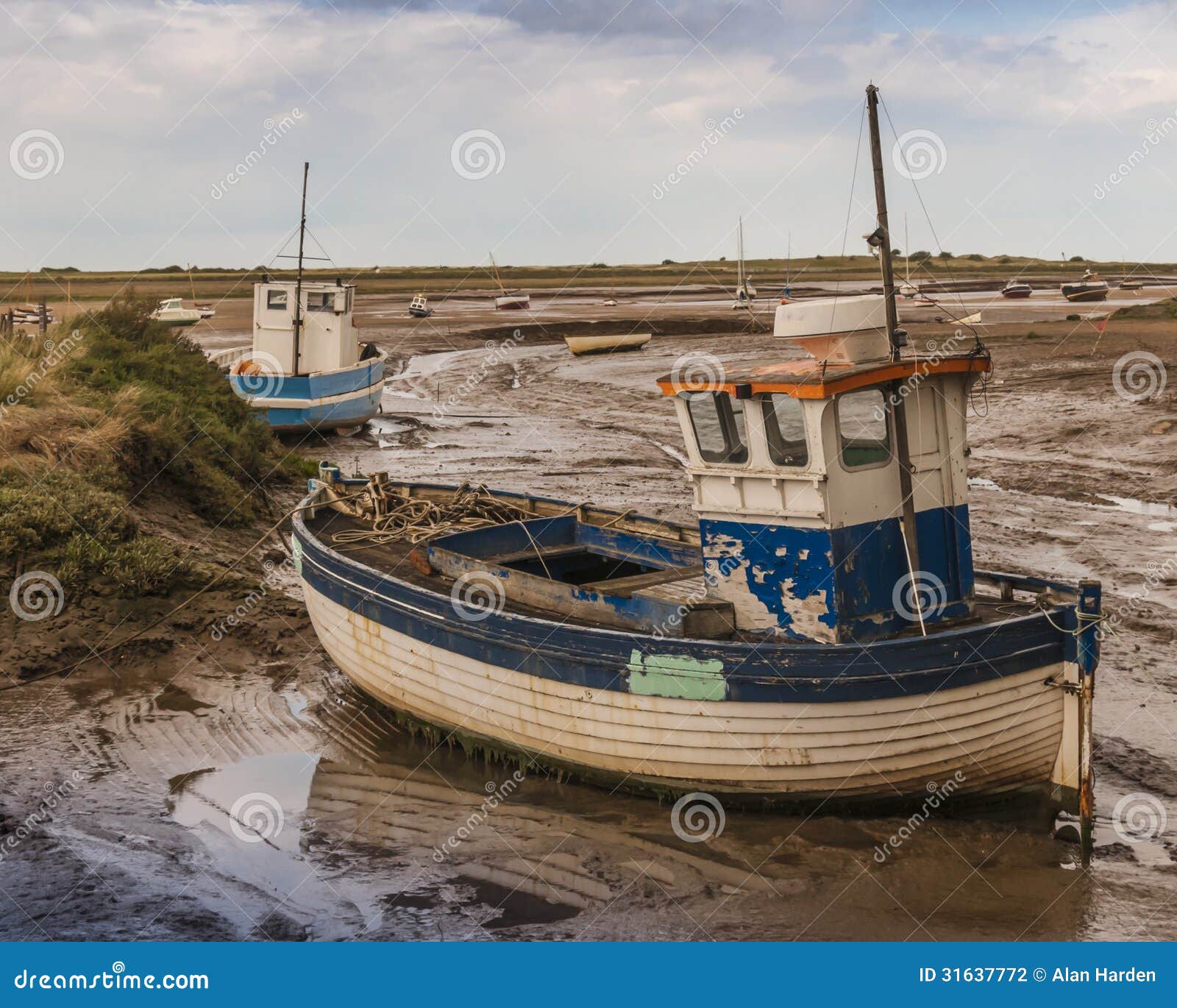 Old wooden fishing boat on mud flats at Brancaster Norfolk England.