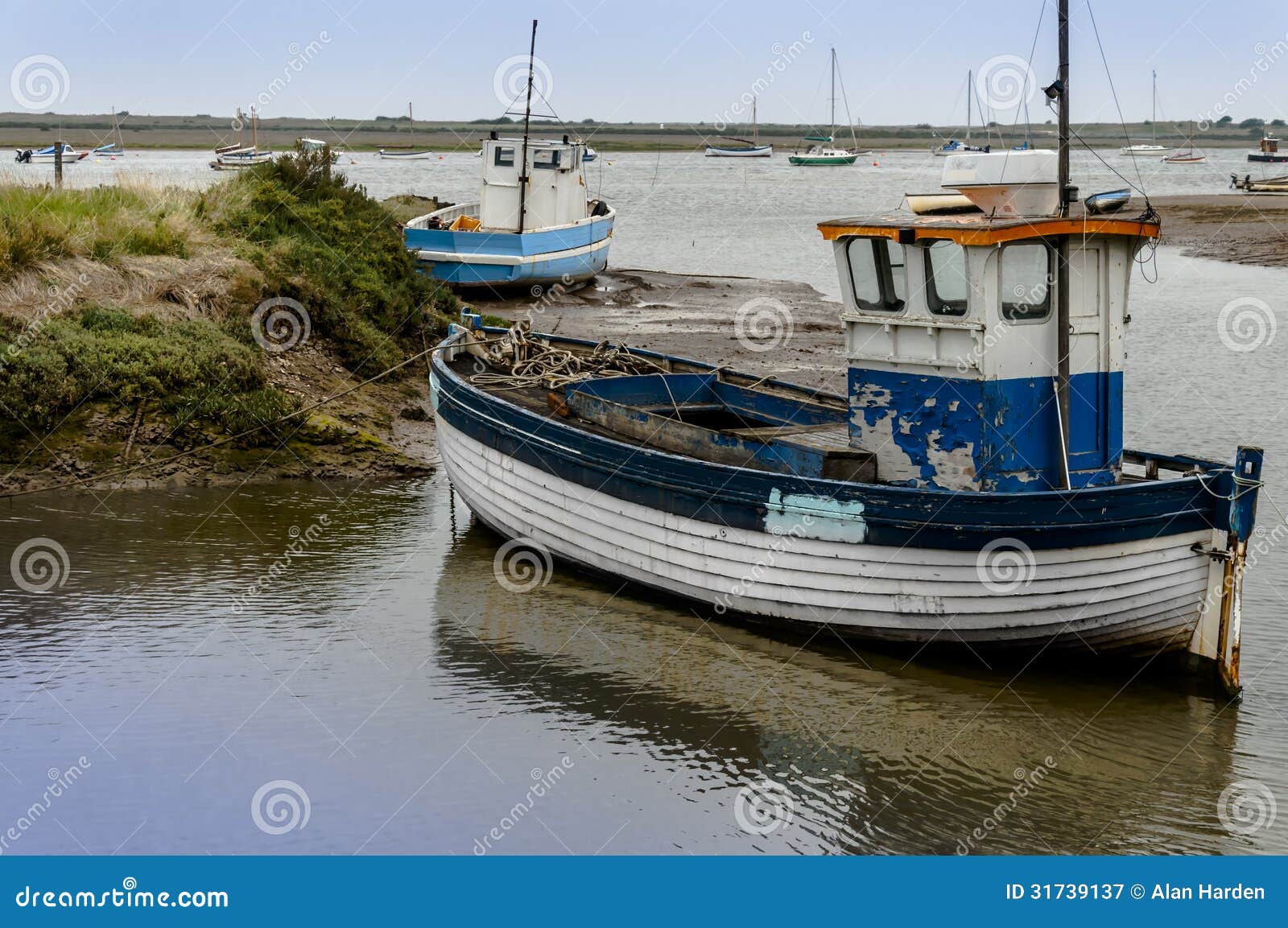 Old wooden fishing boat on mud flats at Brancaster Norfolk England.