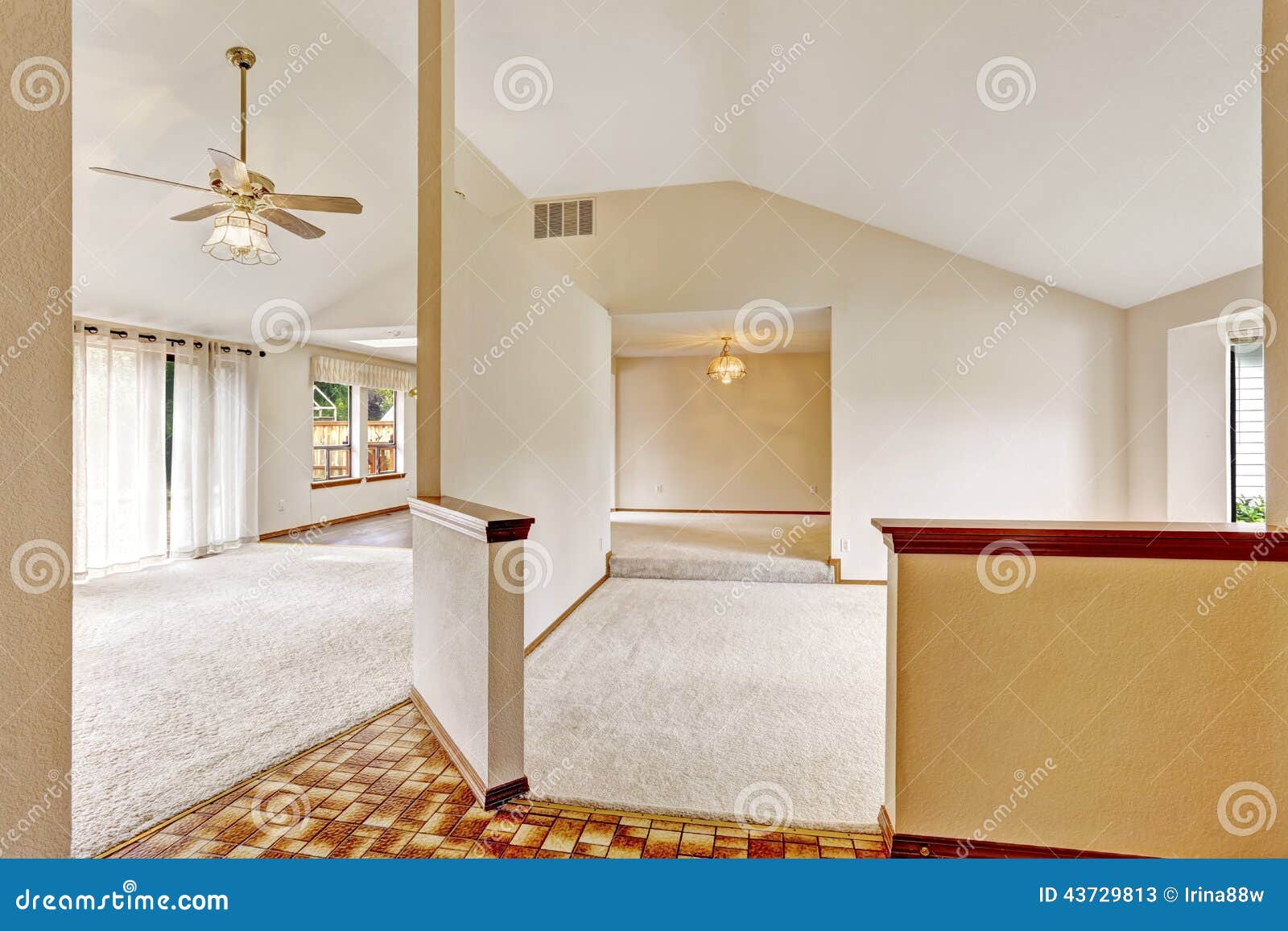 Open floor plan in empty house with vaulted ceiling and carpet floor.