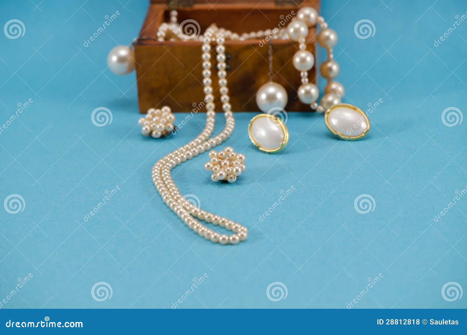 Pearl jewelry beads necklace earring in retro wooden box on blue 