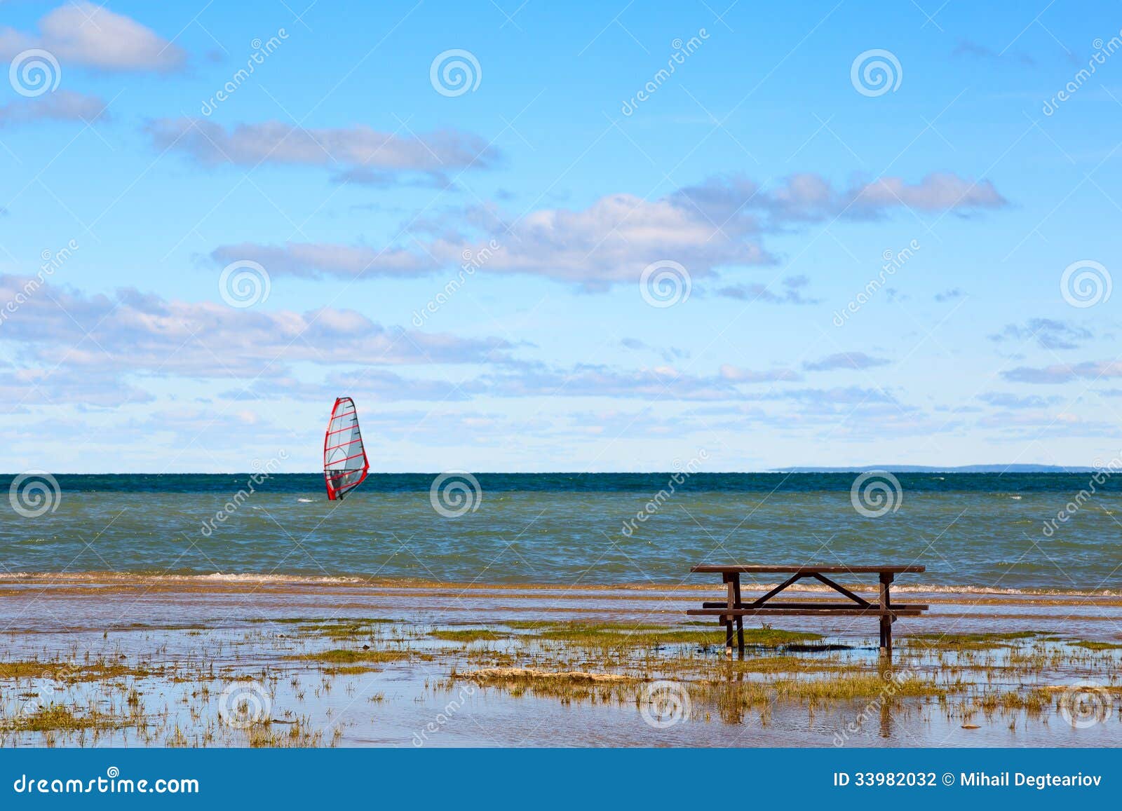 Picnic table on a lake shore with legs slightly flooded by shallow