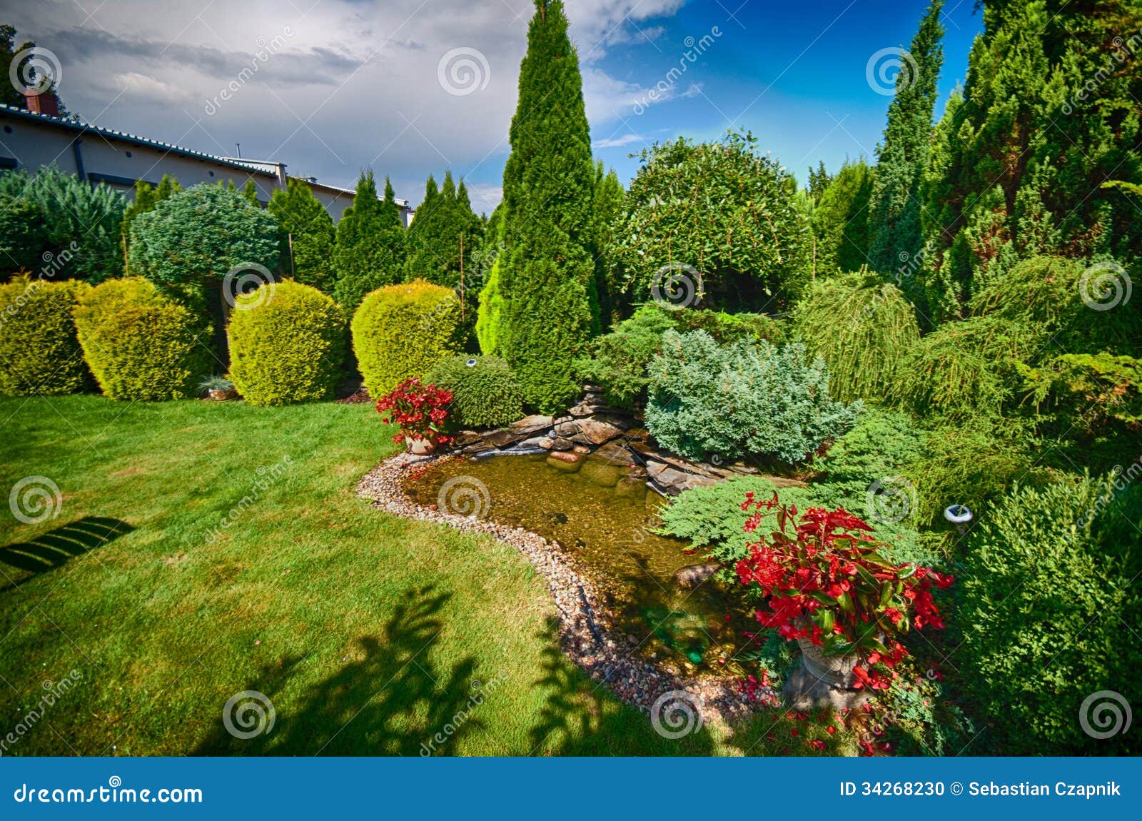 Scenic view of landscaped garden with lawn and pond in foreground.