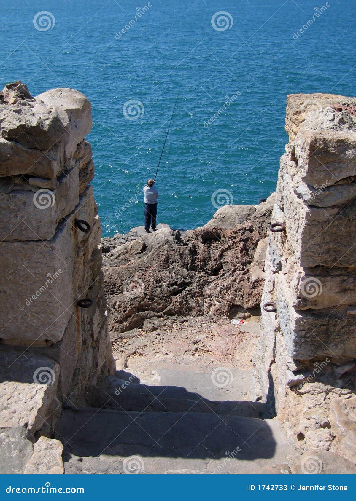 man fishes on rocks at the Boca do Inferno (the westernmost point on 