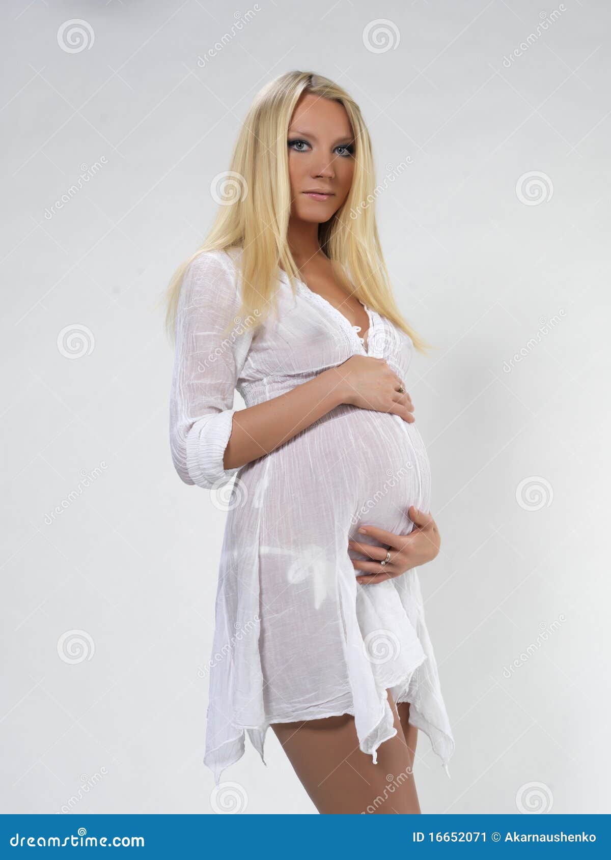 The pregnant young beautiful girl in white clothes on a white ...