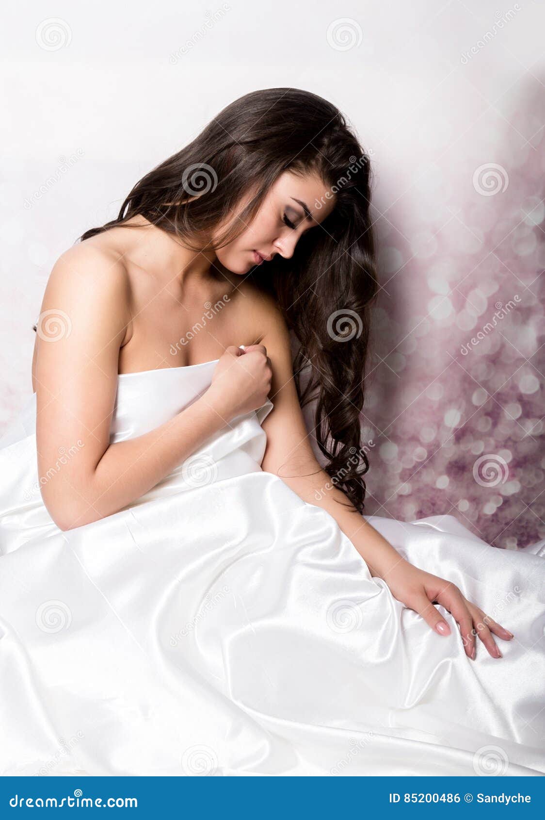 Pretty Female In Peignoir Sleeping On Bed Under Silk Sheets Stock Photo