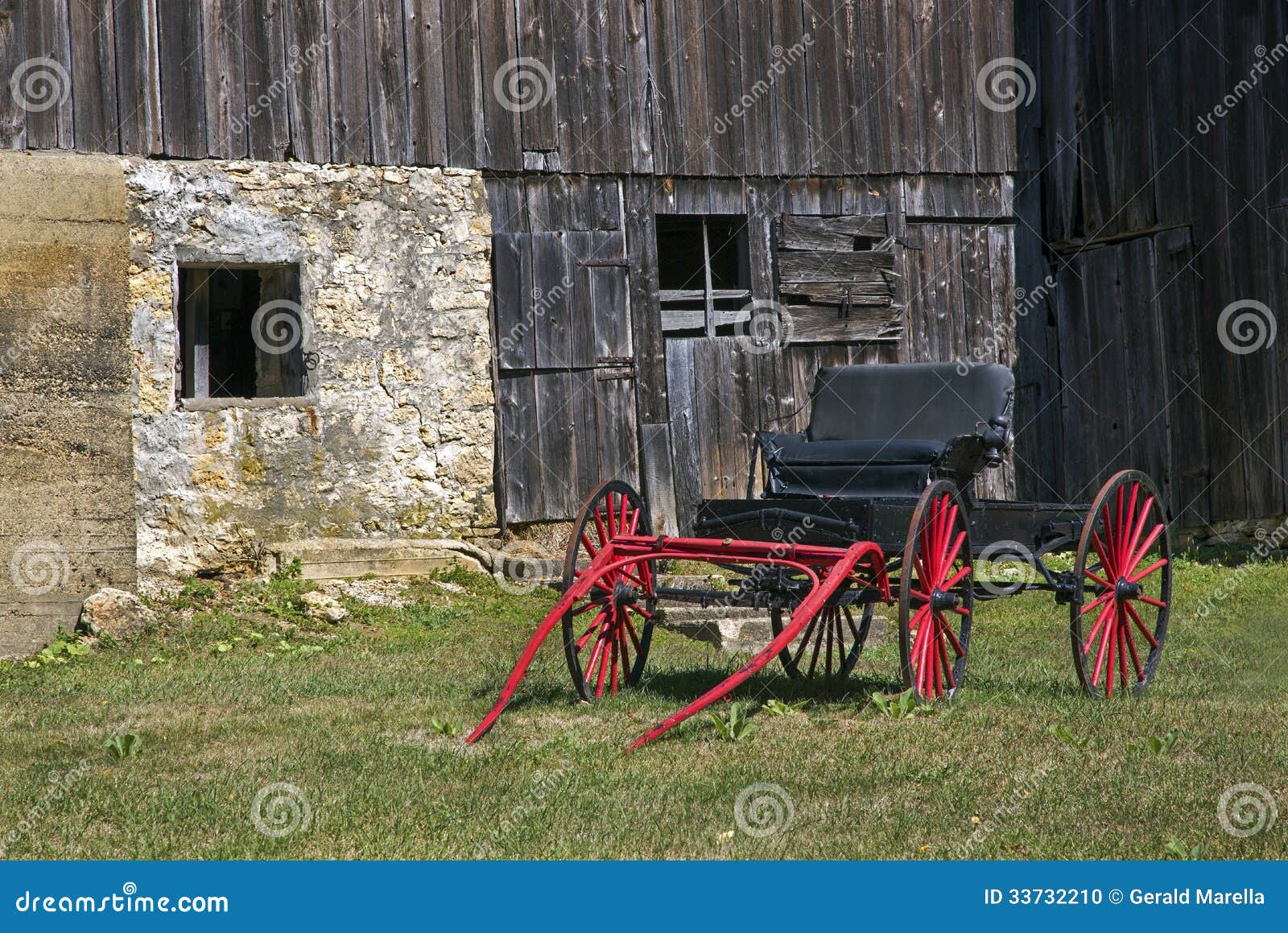 red horse carriage sits in front of a vintage barn.