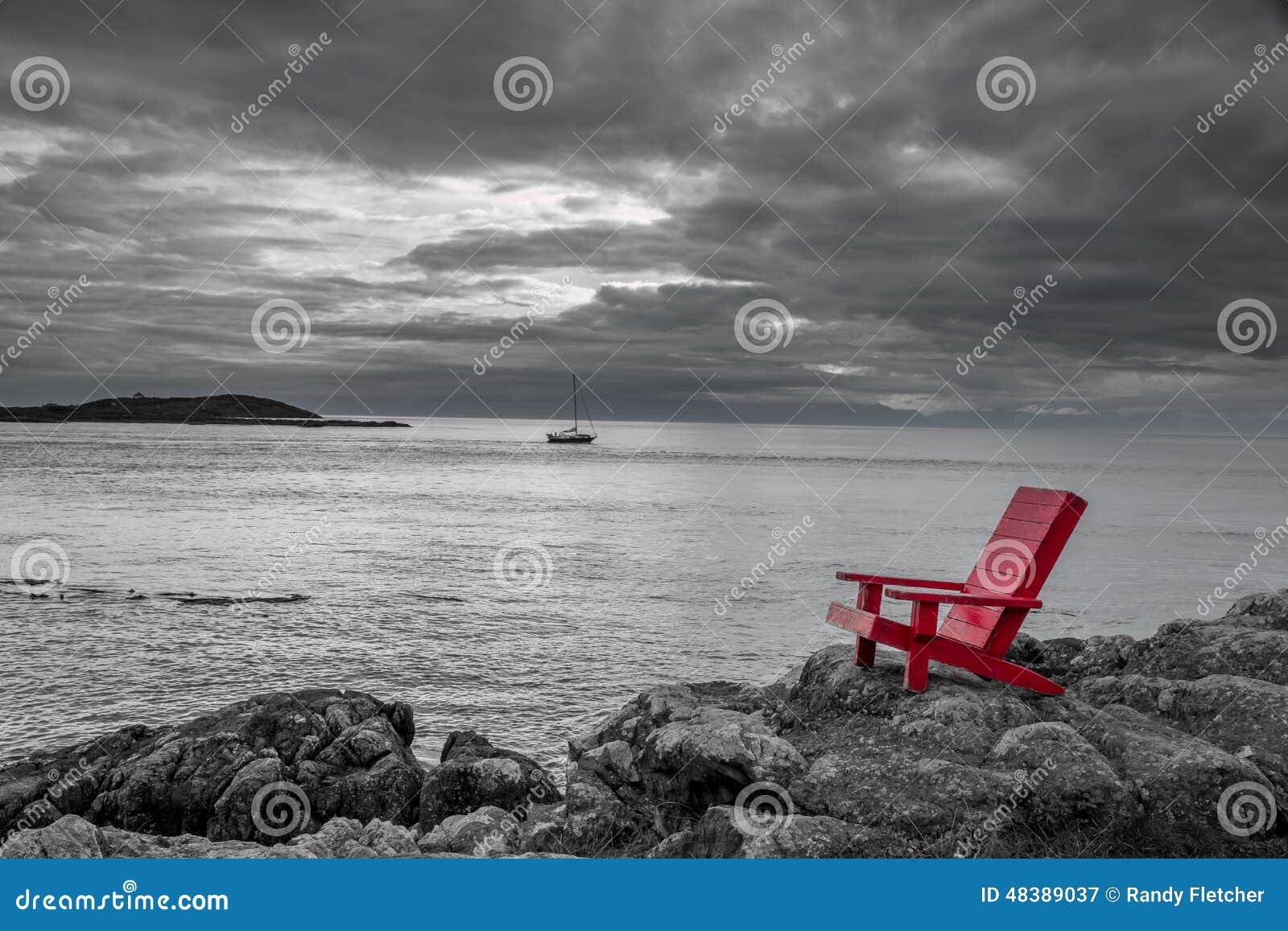red Adirondack chair contrasts with a stormy black and white ocean 