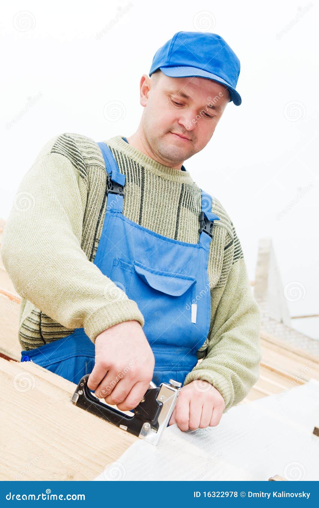 Builder worker at roofing works on tiling with staple gun.