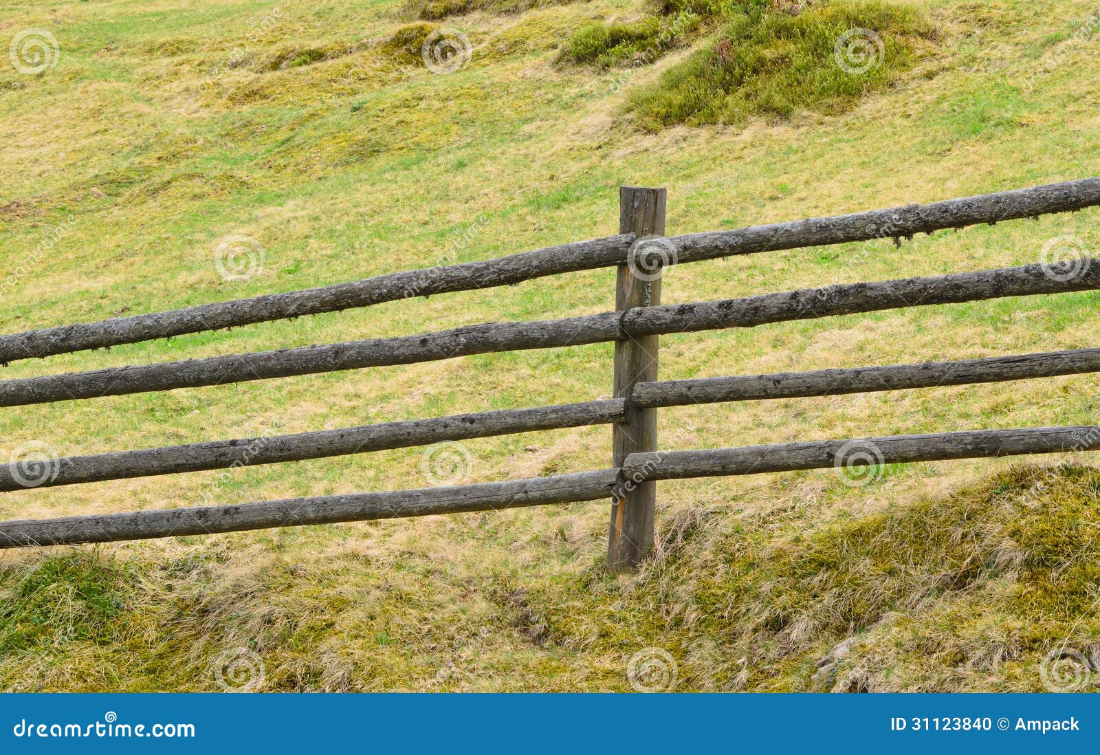 Rustic wooden fence composed of four parallel poles at the foot of a 