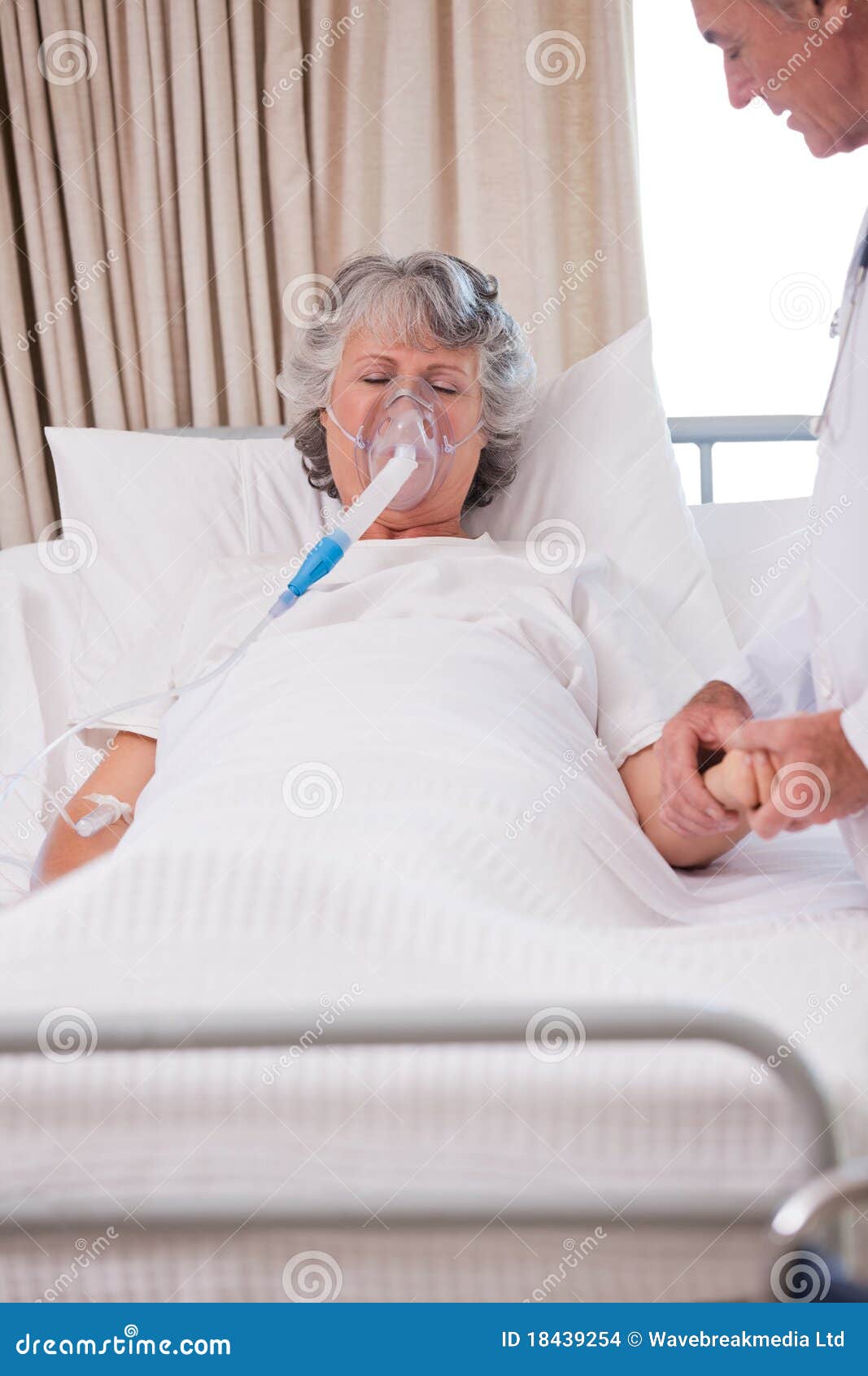 Senior doctor with his sick patient holding her hand.