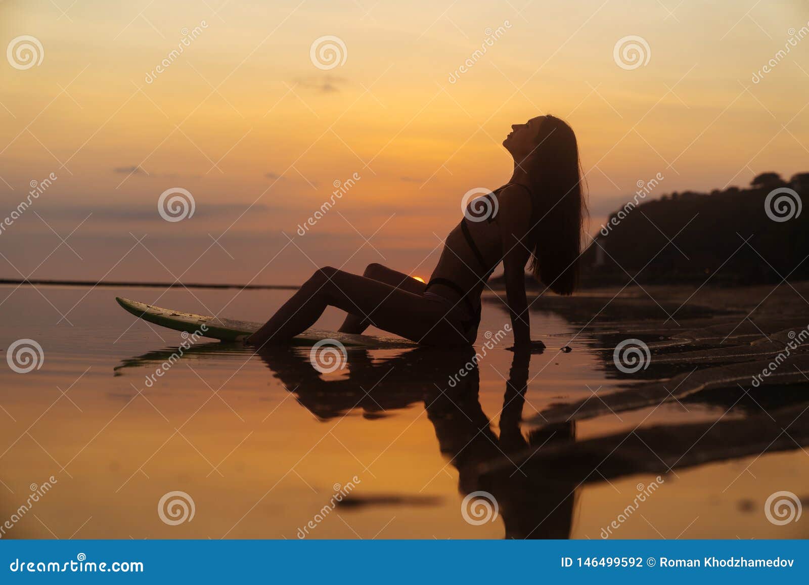 Silhouette Girl In Swimsuit Lying And Posing On Surf Board At Beach