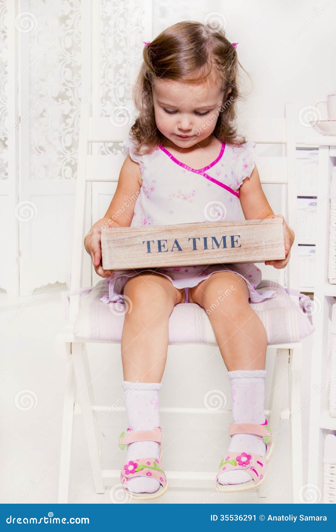 Cute little girl holding a wooden box with tea bags.