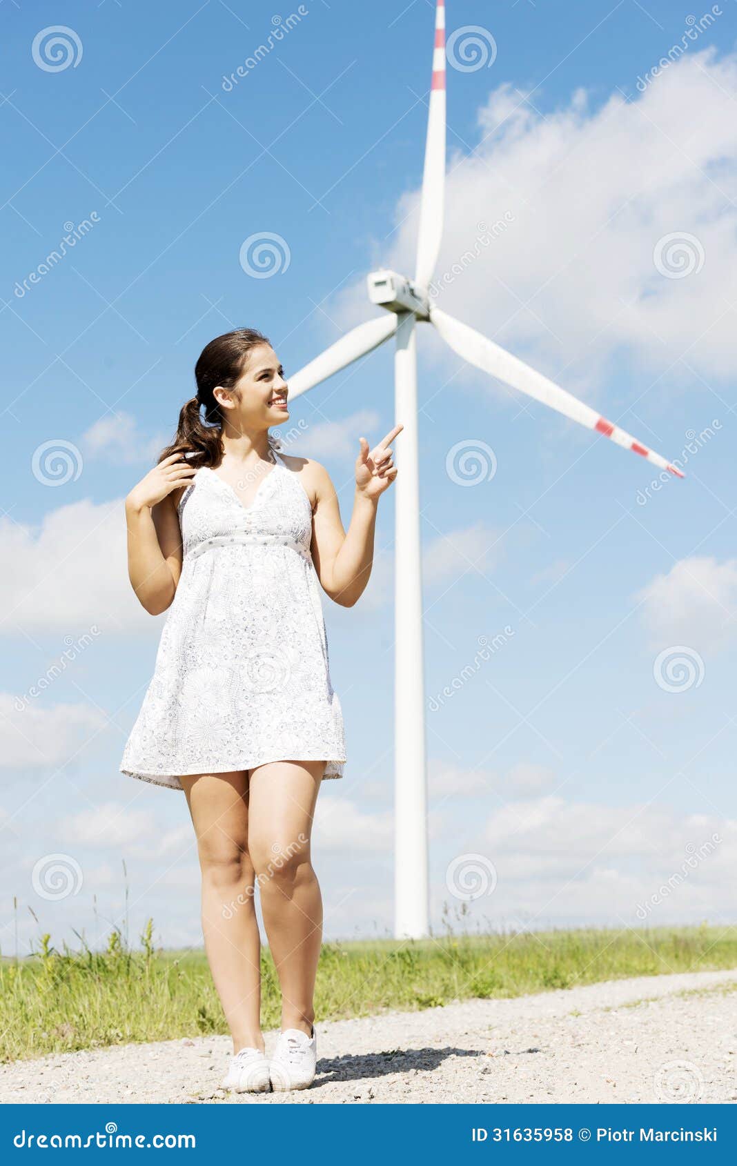Happy teen girl next to wind turbine.Eco energy concept.