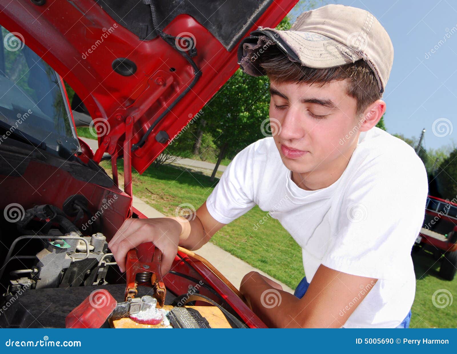 smiling teenage boy working on a truck engine.