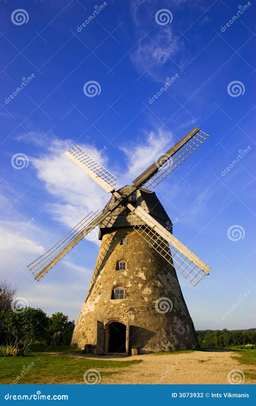 Traditional Old dutch windmill in Latvia against blue sky with white 