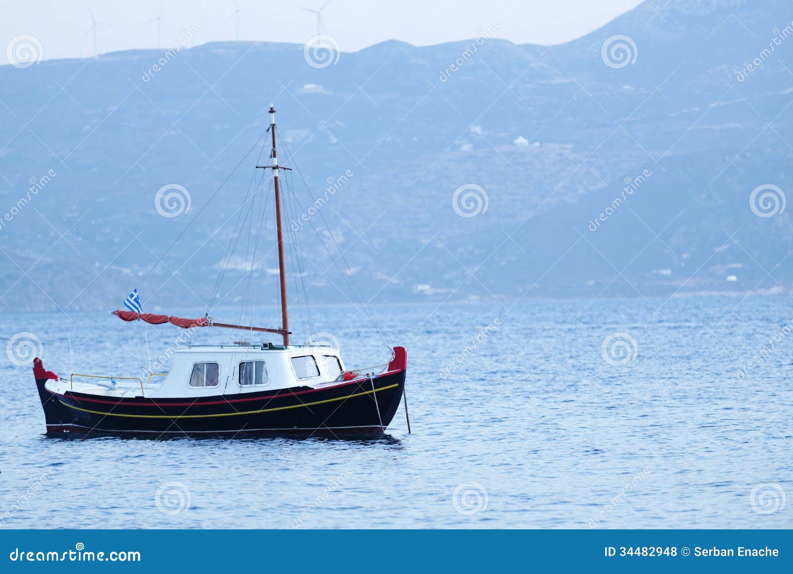 Side view of traditional Greek fishing boat on blue sea with coastline ...