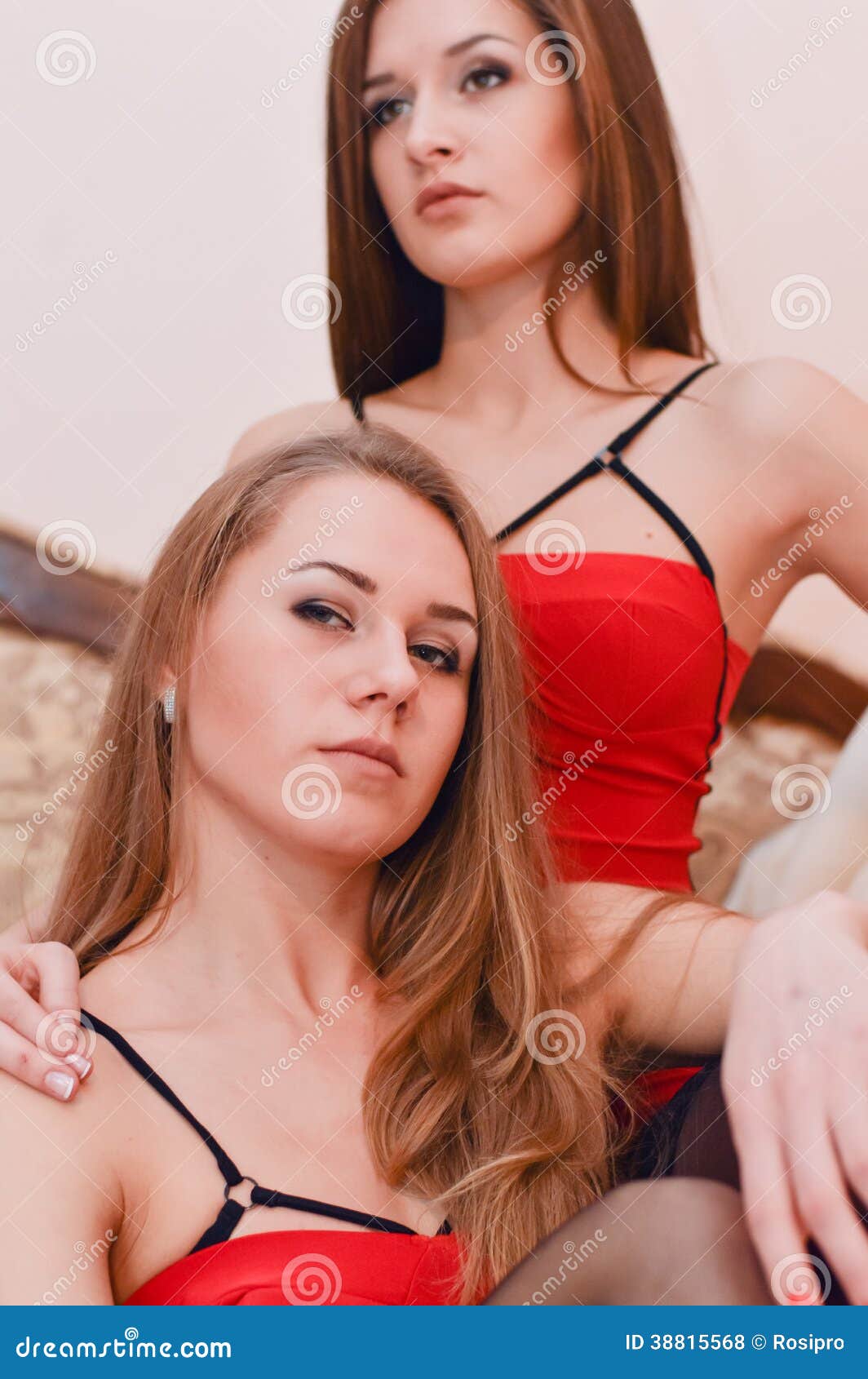 Two Sexy Girl Friends In Red Dress Sitting On The Bed