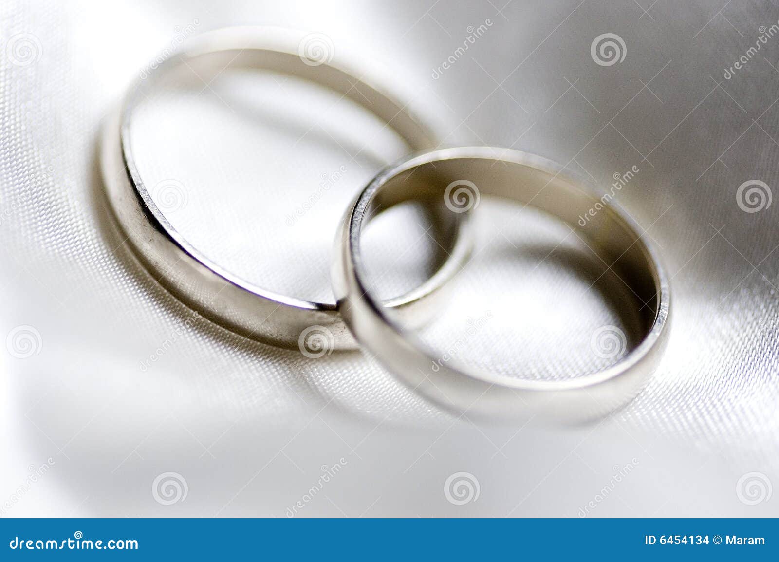 Two silver wedding rings on a white texture.