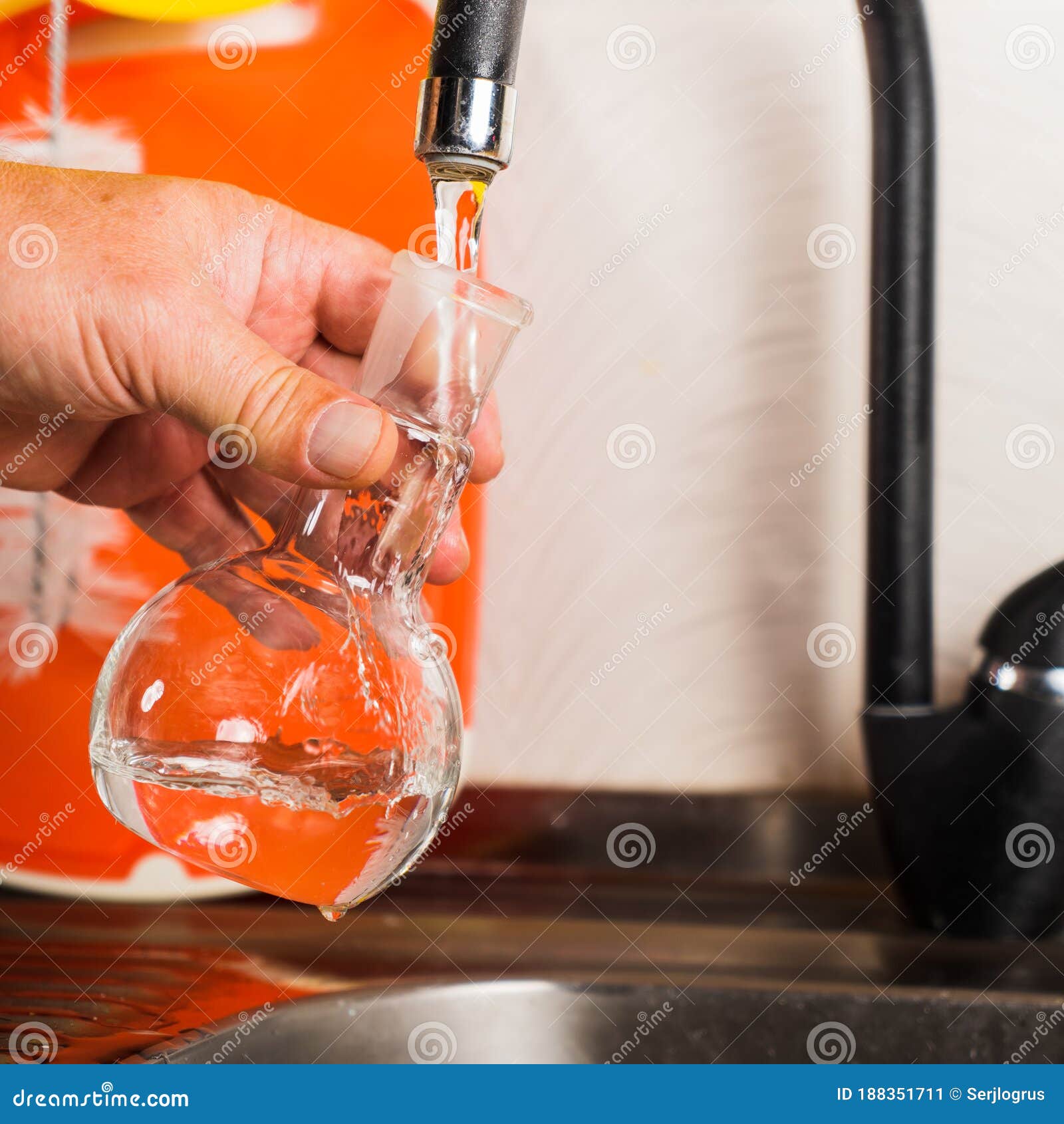 Un Hombre Arroja Agua Del Grifo En Un Matraz De Vidrio Imagen De