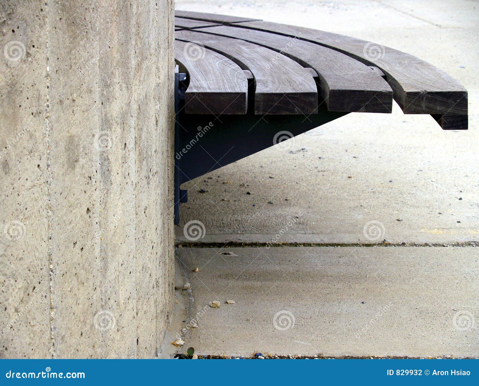 An urban plaza bench made of wood and concrete in strong light, shadow 