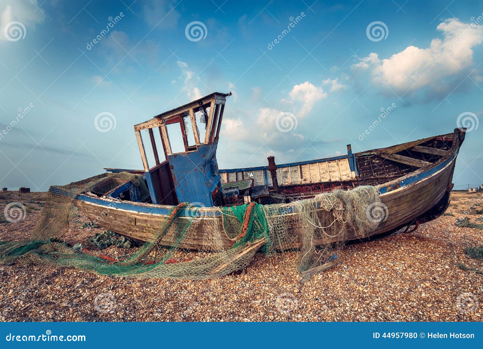 Old wooden fishing boat washed up on a shingle beach.