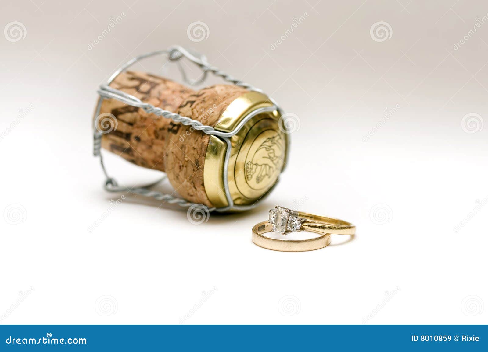 wedding and engagement ring with a champagne cork on white ...