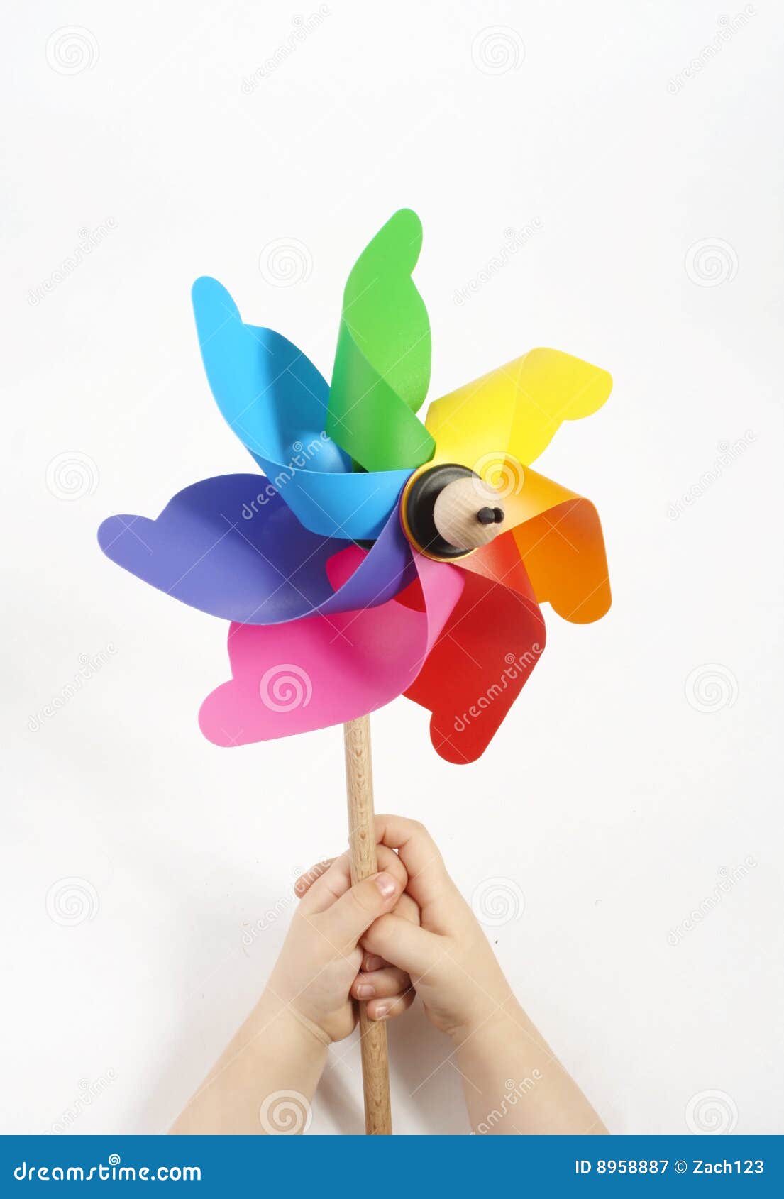 Kids hands holding a windmill with lots of color an a white background 