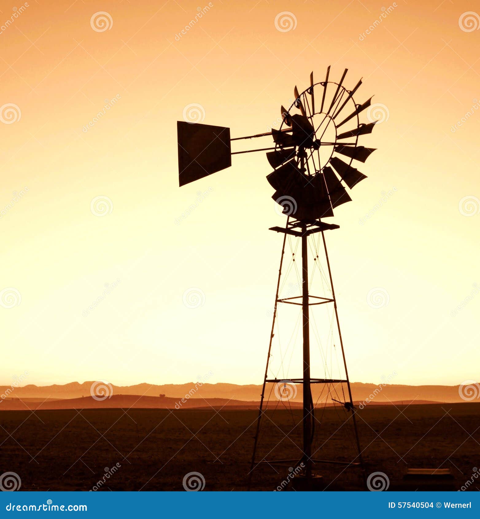 Landscape with windmill water pump at sunrise.