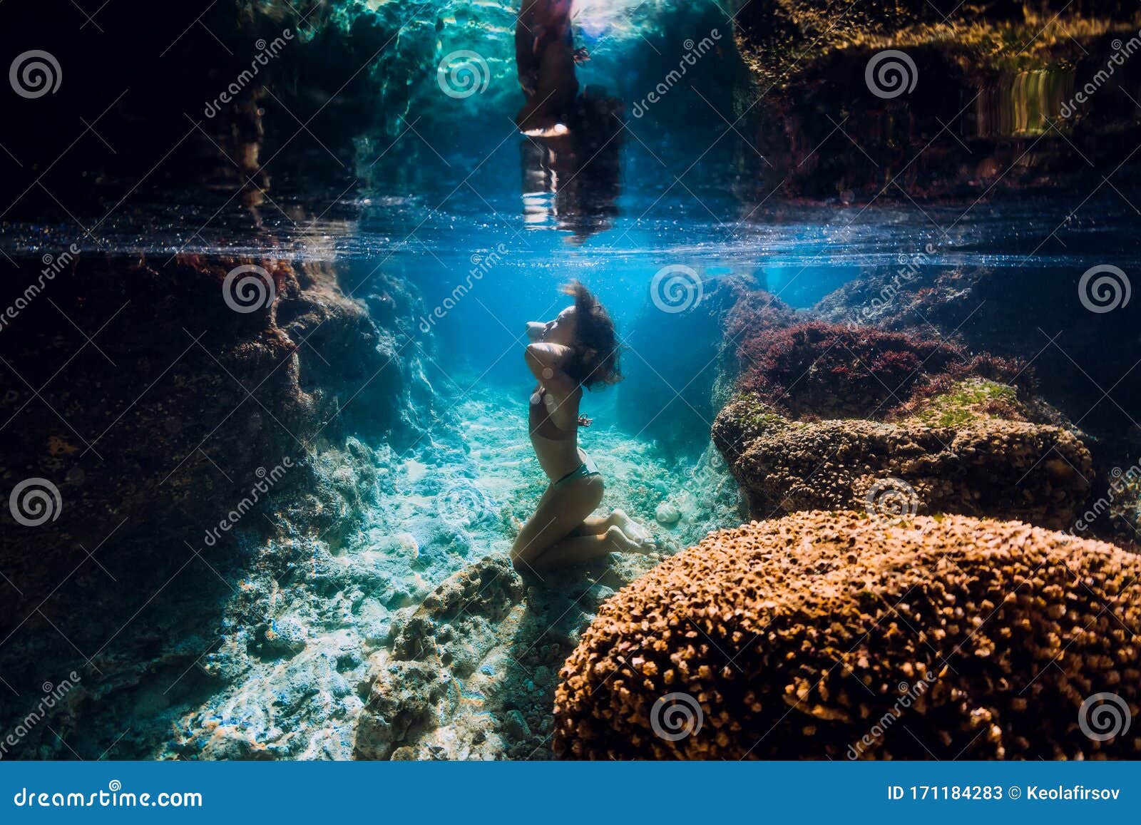 Woman In Bikini Posing Underwater Near Corals In Blue Ocean Stock