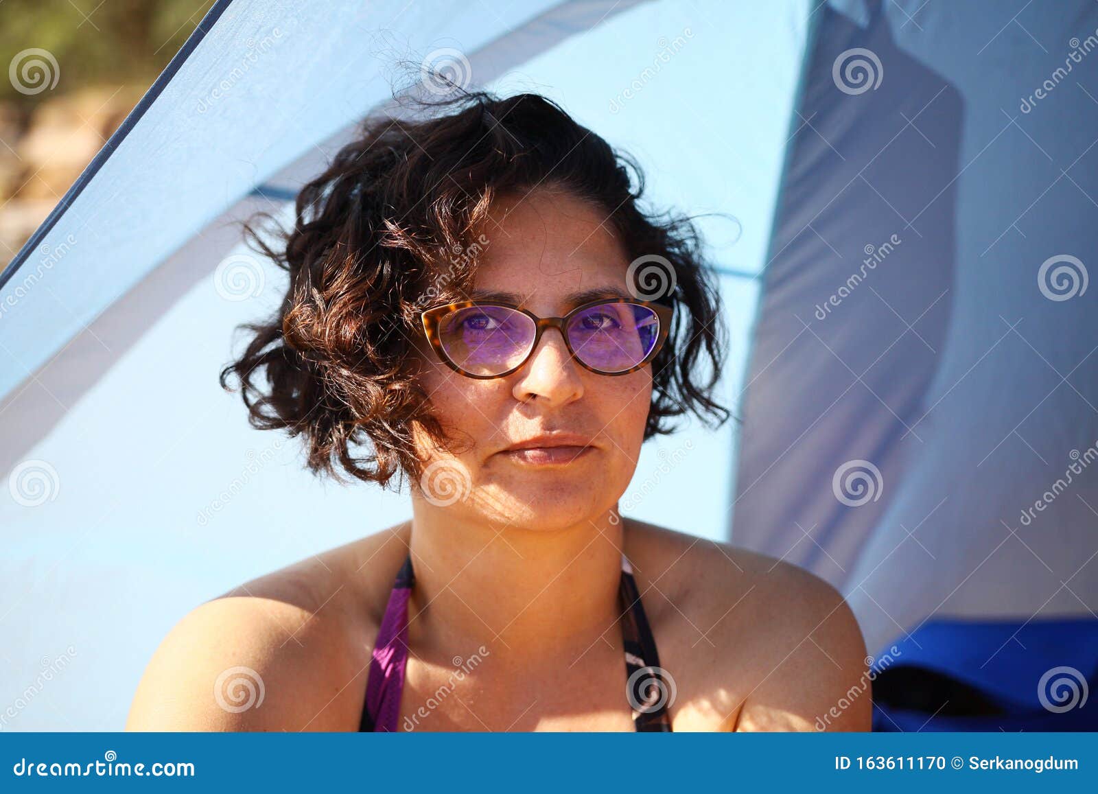 Woman With Glasses Staring At The Camera In The Beach Tent Stock Photo