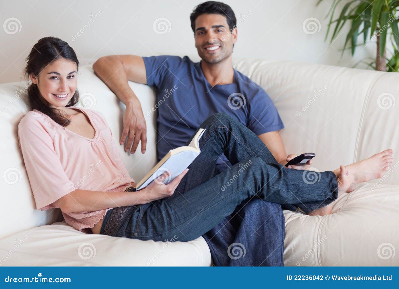 Woman Reading A Book While Her Husband Is Watching TV ...