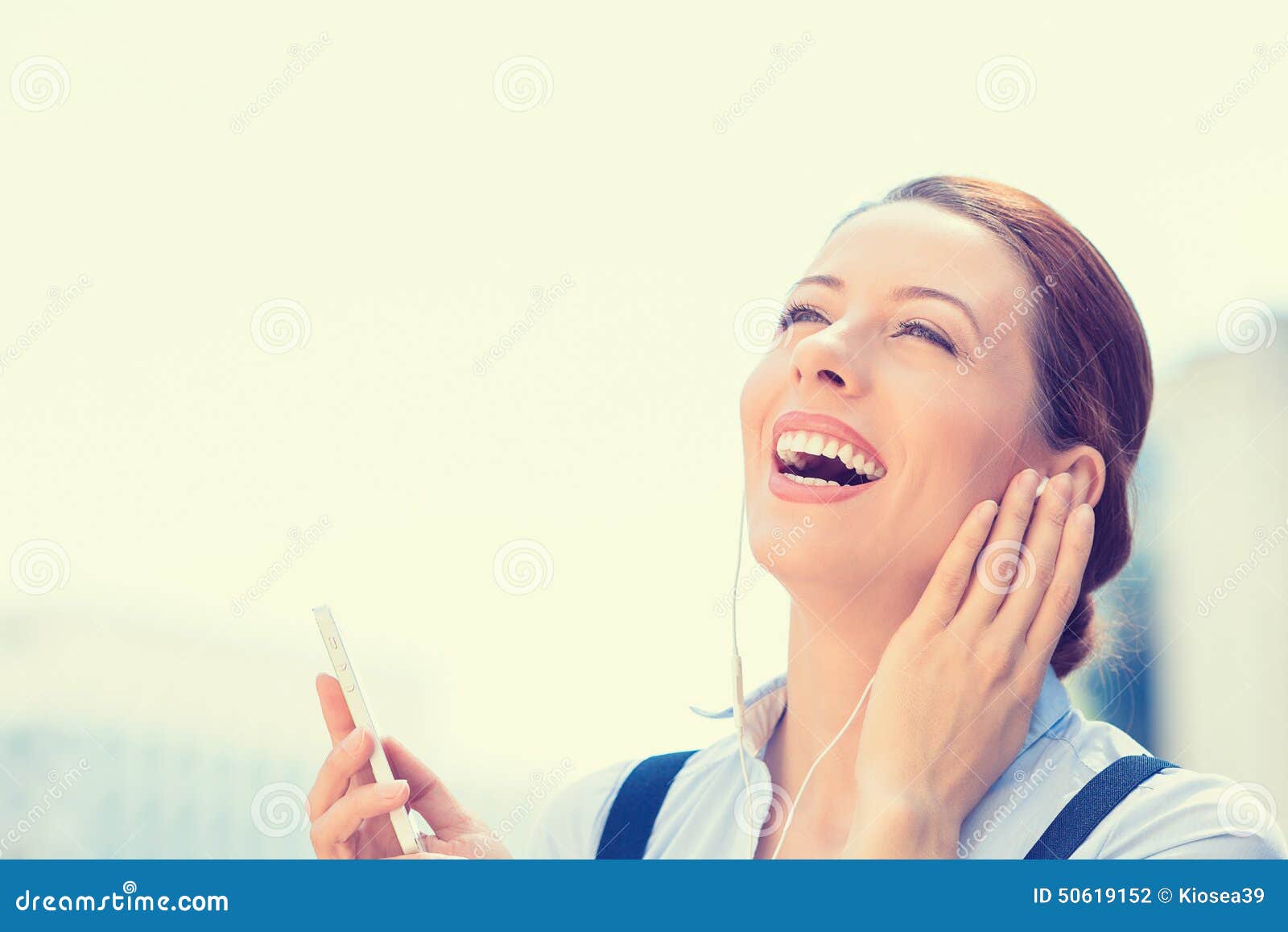 Woman walking on street listening music on mobile smart phone - woman-walking-street-listening-music-mobile-smart-phone-closeup-portrait-attractive-smiling-business-outdoor-laughing-50619152