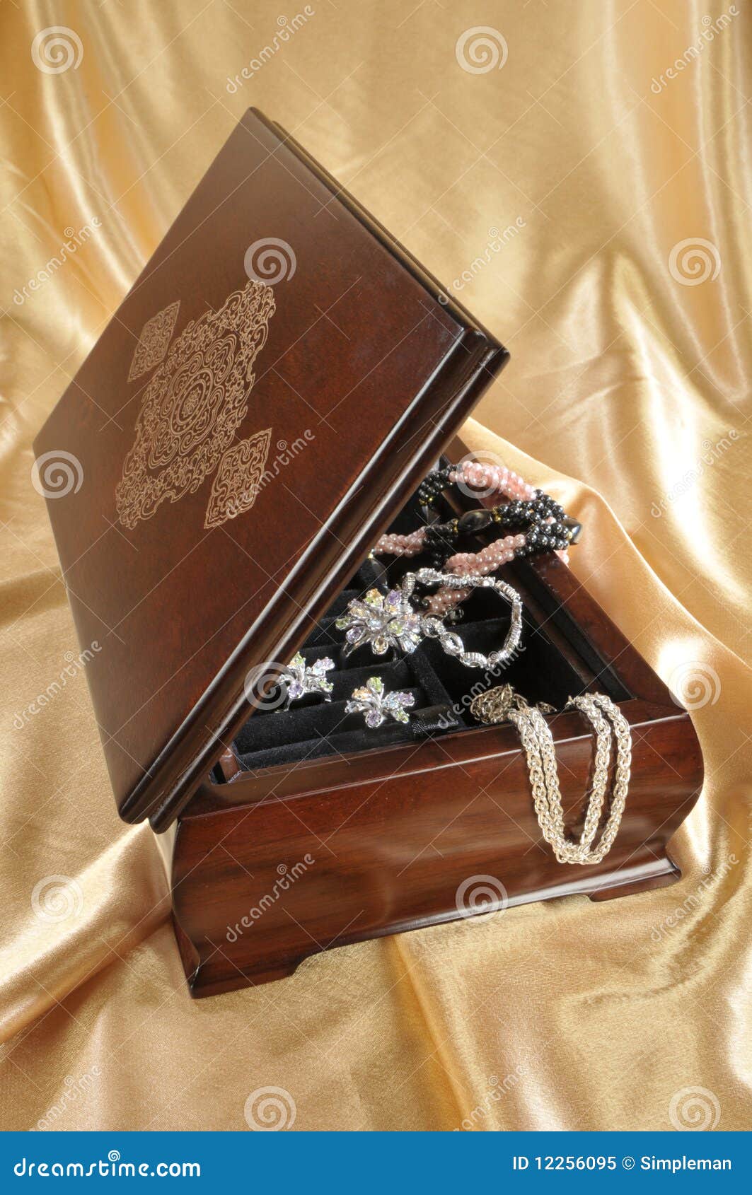 Close-up of wooden box with jewelry on golden background.