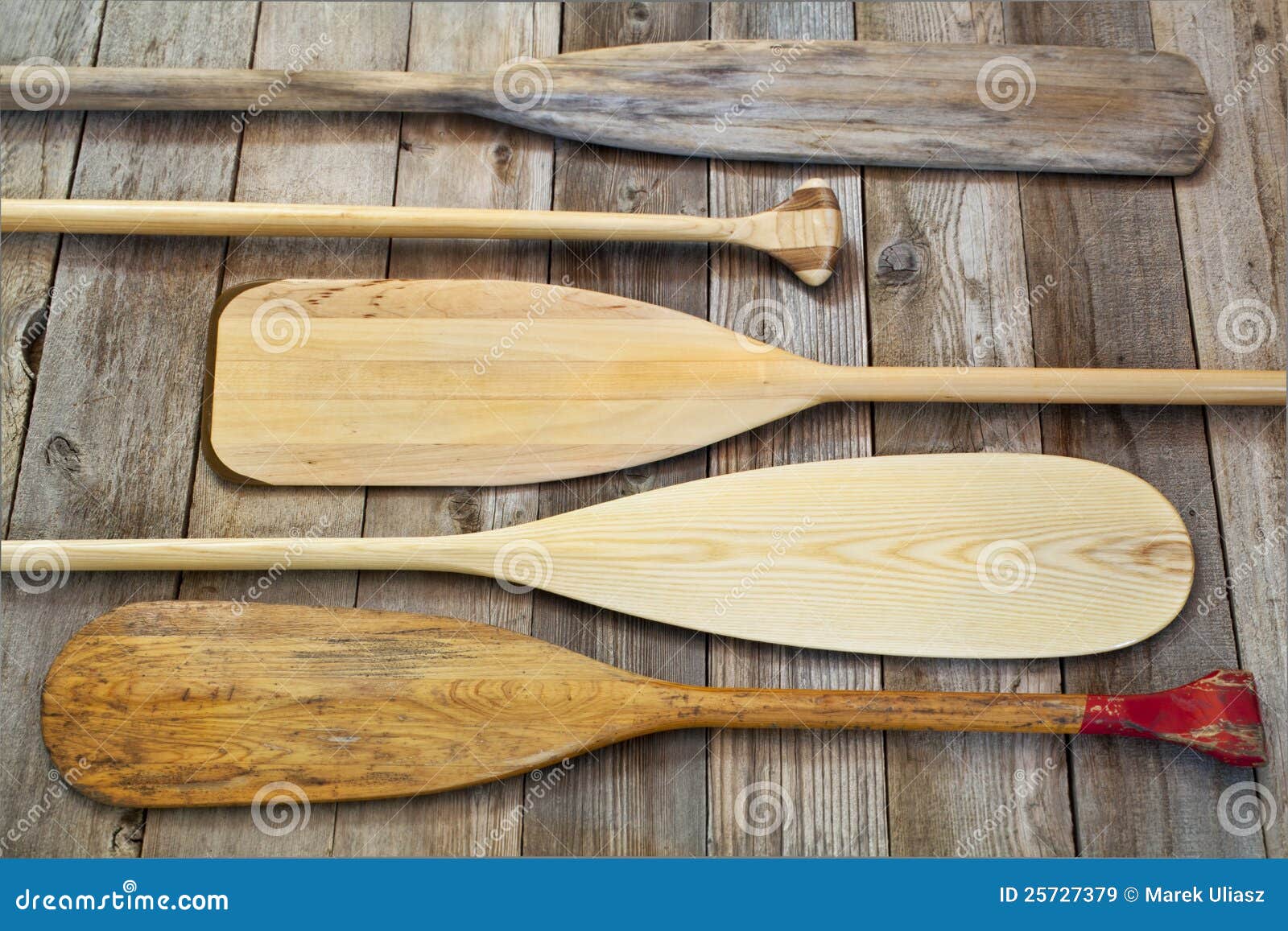 Blades and grips of wooden canoe paddles of different shape against 