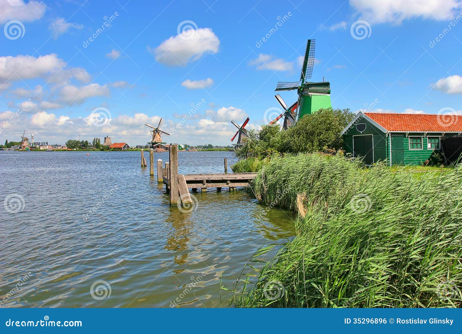 Wooden windmills along river under beautiful blue sky with white 