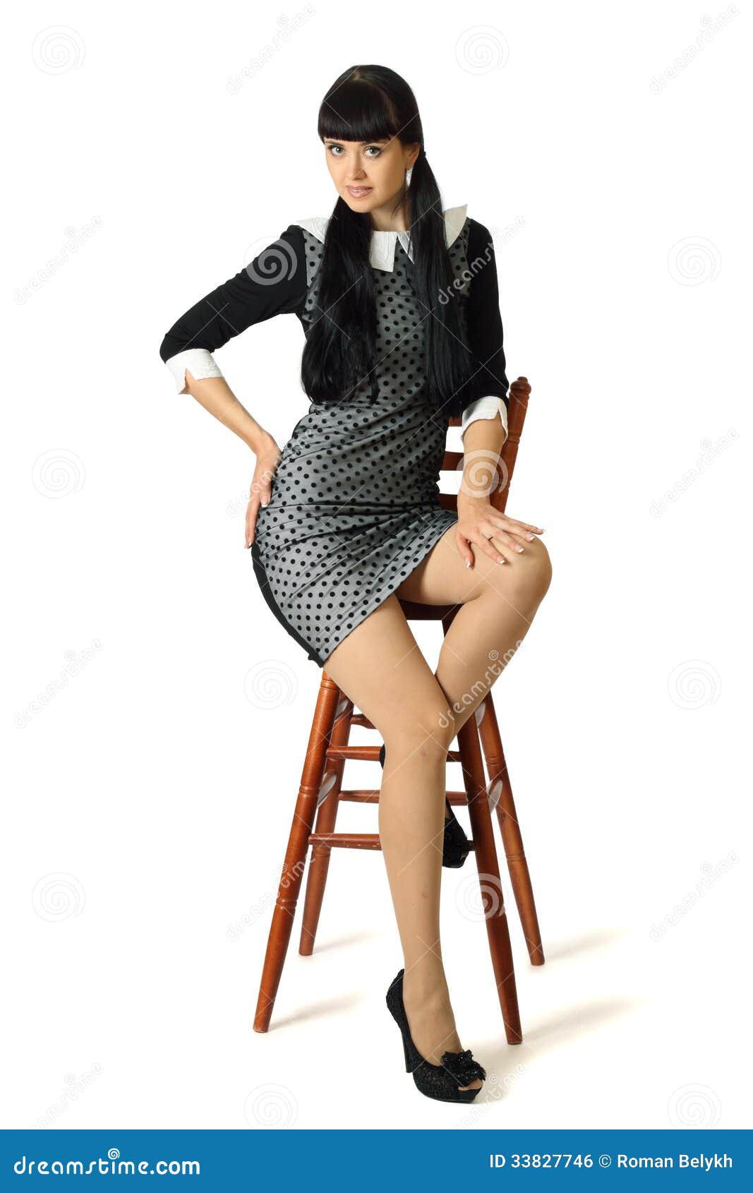 Young beautiful woman in cocktail dress is sitting on high woode