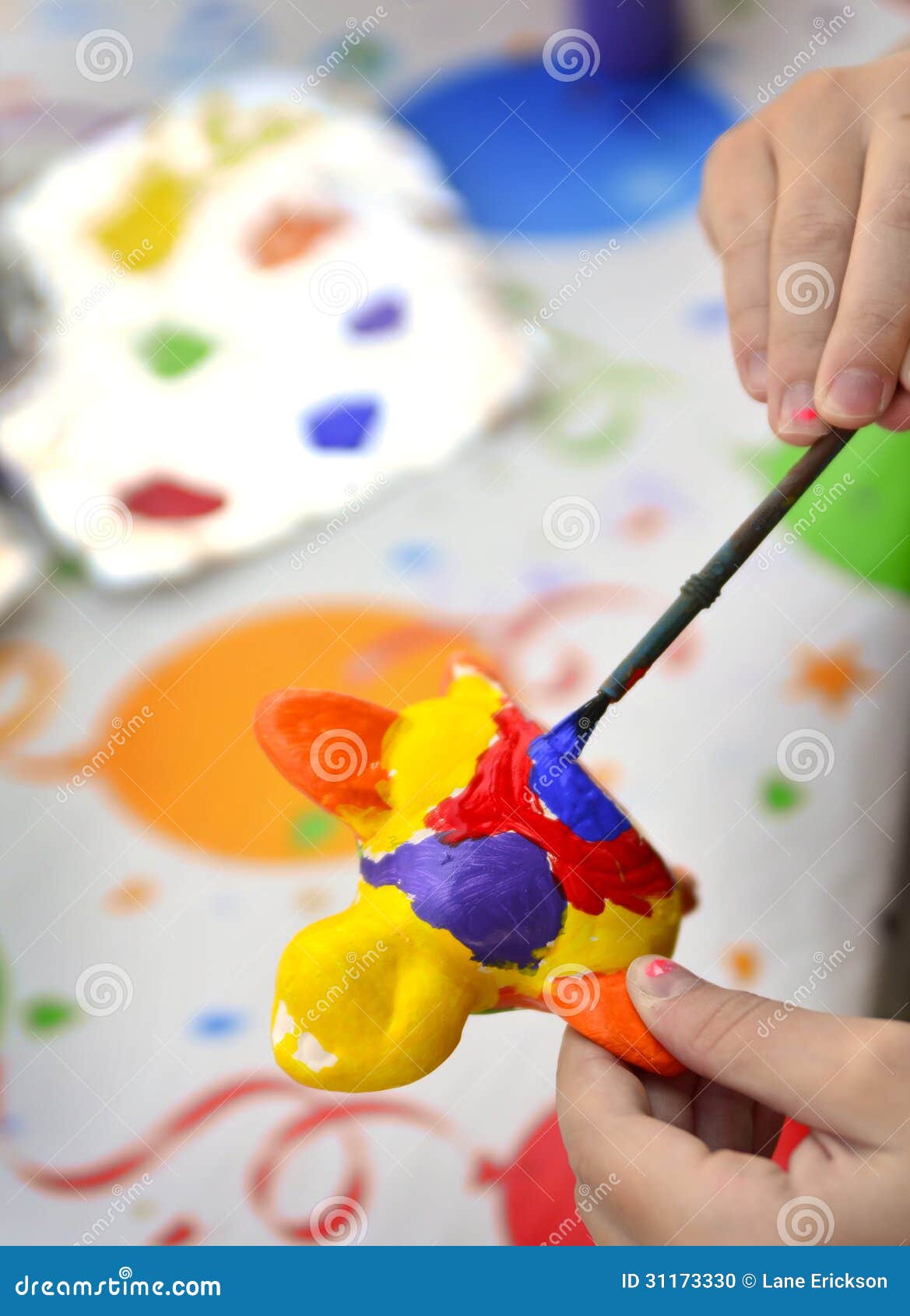 Young girl artist painting with paints and brushes at art table.