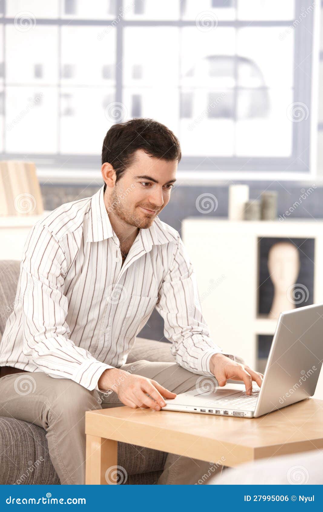 young-man-browsing-internet-home-smiling-27995006.jpg