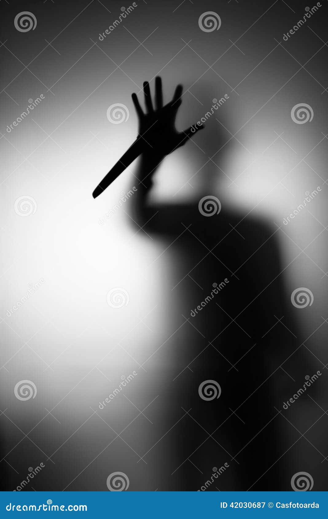 在毛玻璃后的危险人与在他的handn的一把刀子.