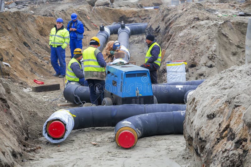 Équipe De Travailleurs Dans Un Fossé Installant Le Tuyau De Chauffage  Urbain Photo éditorial - Image du métal, environnement: 106503116