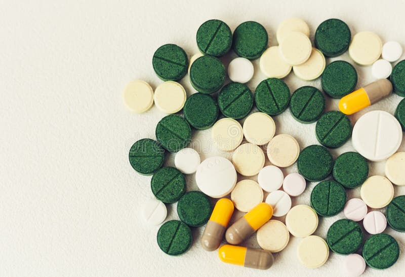 Медицина зеленая, пинк и желтые таблетки или капсулы на белой предпосылке с...