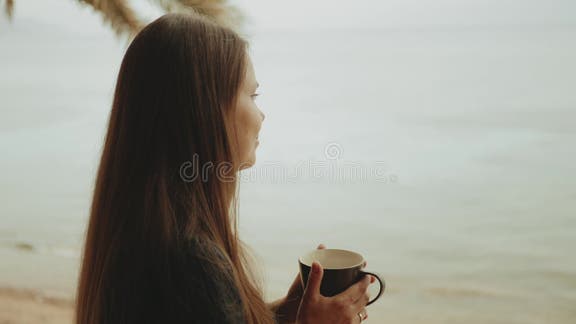 μόνη γυναίκα πίνει καφέ ή τσάι το πρωί στο μπαλκόνι με θέα μπλε θάλασσα από  το παράθυρο ταχεία εικόνα απόθεμα βίντεο - Βίντεο από alon: 179007055