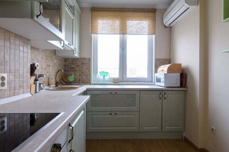 γωνιακή κουζίνα με παράθυρο σε μικρό διαμέρισμα. ξύλινα έπιπλα σε θερμούς  τόνους. Στοκ Εικόνα - εικόνα από : 194560055