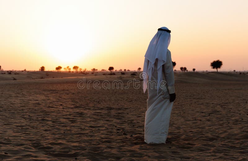 Арабы стоят один в пустыне и смотрят за закатом солнца Стоковое Изображение - изображение насчитывающей закат, сафари: 159165653
