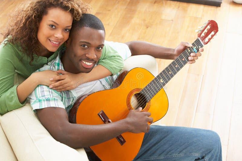 Гитара соединила семью. A smiling White man sitting on the Sofa and is playing the Guitar. Лучшие подружки на гитаре