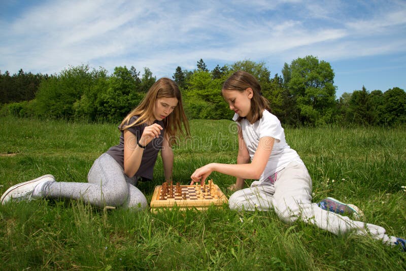 Играем с сестрой в карты на раздевание. Девочка сидит на траве. Две подружки на траве. Игра в шахматы на природе. Две девушки на траве.